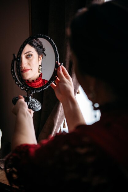 Retrato de mujer hermosa en ropa roja vintage s temprano con espejo