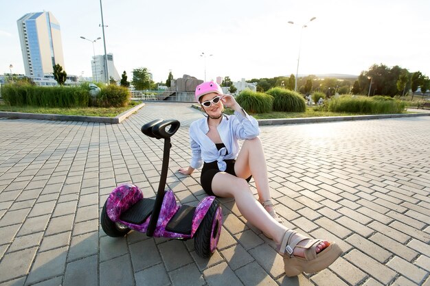 Foto retrato de una mujer hermosa en un scooter hoverboard o gyro en el parque