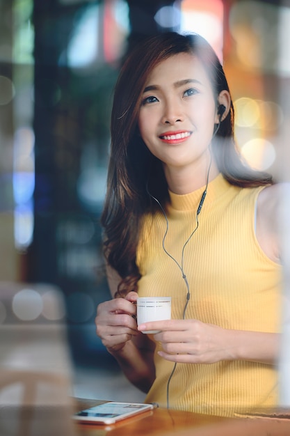 Retrato de mujer hermosa sentada en el café con luz de noche