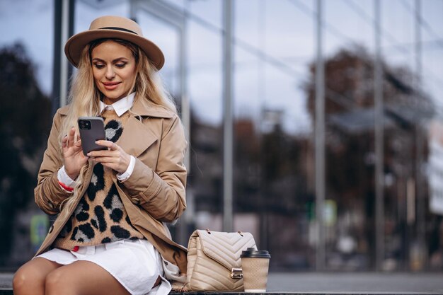 Retrato de mujer hermosa sentada en las escaleras y usando el teléfono