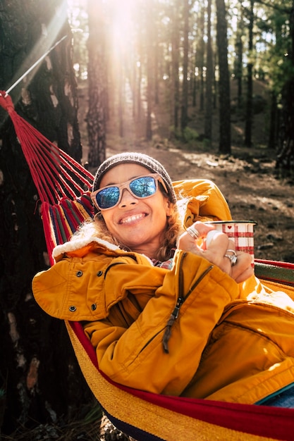 Retrato de mujer hermosa sonríe y disfruta de relajación y libertad actividad de ocio al aire libre en el parque de bosques forestales - árboles altos y luz del sol en backgorund - alegres mujeres al aire libre