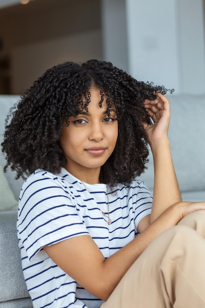 Retrato de una mujer hermosa sonriendo en casa mujer africana en casual mirando a la cámara con espacio de copia alegre chica de raza mixta relajándose en casa con una gran risa