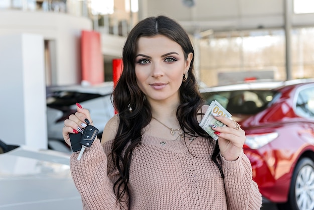 Retrato de mujer hermosa sosteniendo las llaves del coche en el showroom