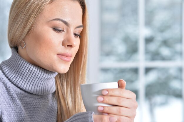 Retrato de mujer hermosa sosteniendo una taza en casa