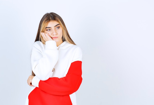 Retrato de una mujer hermosa en sudadera con capucha caliente de pie y pensando