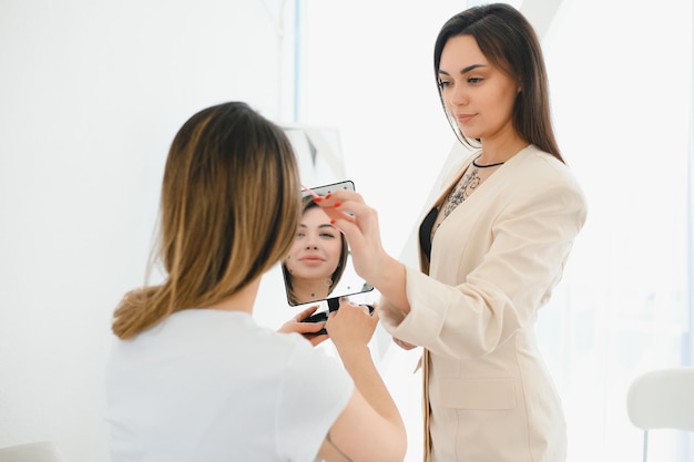 Retrato de una mujer hermosa, sus labios están pintados con lápiz labial rosa mirándose en el espejo