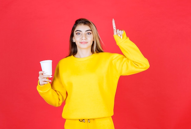 Retrato de mujer hermosa en traje amarillo posando con taza de té