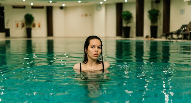 Retrato de mujer hermosa en traje de baño relajante en el spa de la piscina.