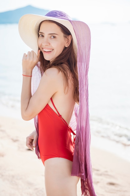 Retrato de mujer hermosa en traje de baño rojo relajante en la playa