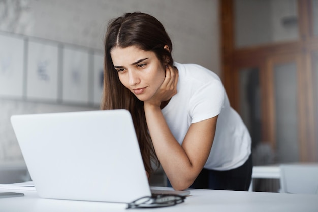 Retrato de mujer hermosa usando una computadora portátil mirando fotos de fiesta de una despedida de soltero con una sonrisa