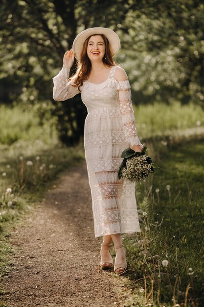 Retrato de una mujer hermosa con un vestido blanco y un sombrero con lirios del valle Una niña en la naturaleza Flores de primavera