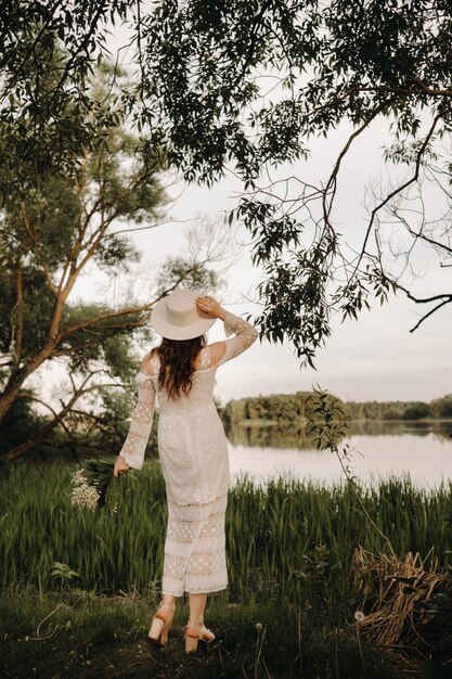 Retrato de una mujer hermosa con un vestido blanco y un sombrero con lirios del valle una niña en la naturaleza