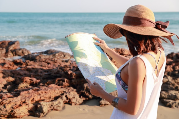 Retrato de mujer hermosa viajero mirando y revisando el mapa en la playa de la isla