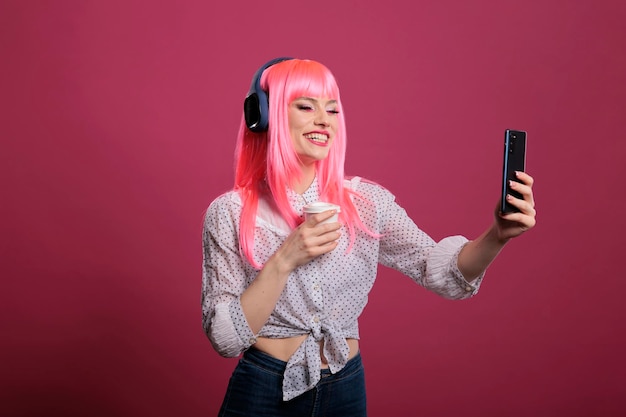 Retrato de una mujer hipster escuchando música y tomando fotos, usando una aplicación de teléfono móvil para divertirse con las fotos. Haciendo fotografía y auriculares inalámbricos, sintiéndome feliz y positivo.