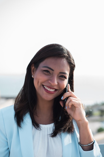 Retrato de una mujer hispana hablando por teléfono y mirando a la cámara