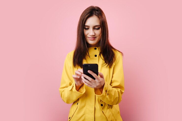 Retrato de mujer con impermeable amarillo usando un smartphone moderno