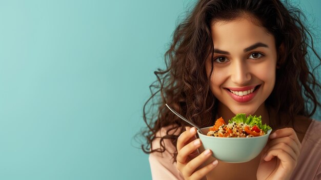 Retrato de una mujer india feliz y casual comiendo una sabrosa ensalada de verduras frescas aislada sobre un fondo azul