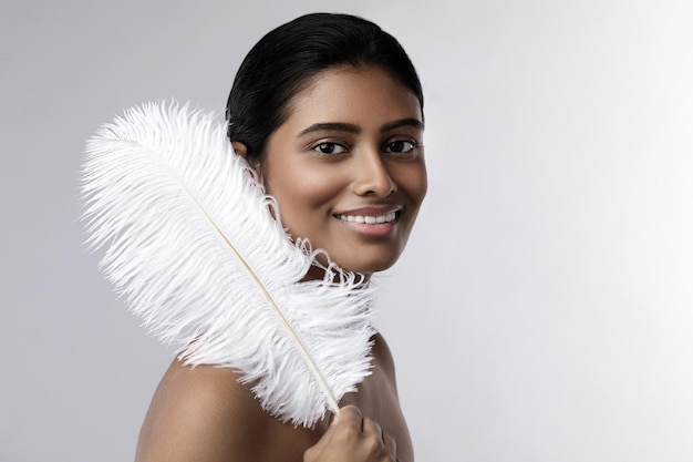 Retrato de mujer India joven y sensual con una suave pluma de avestruz