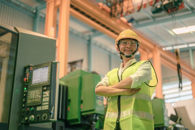 Foto retrato de mujer ingeniera con un casco, gafas de seguridad de pie en una planta industrial