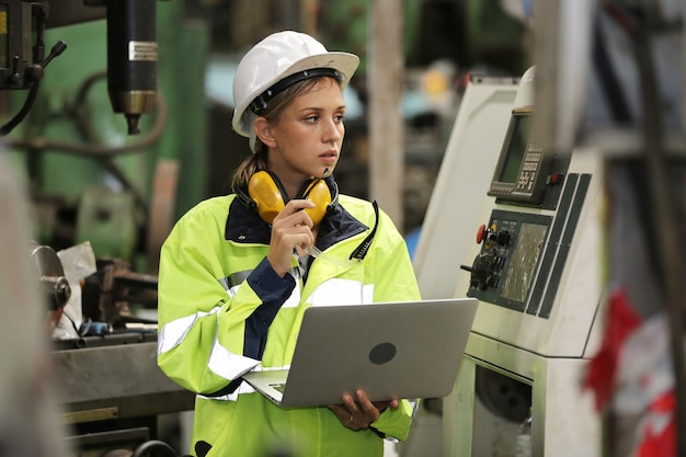 Retrato de mujer ingeniera máquina de funcionamiento por ordenador portátil en la fábrica.