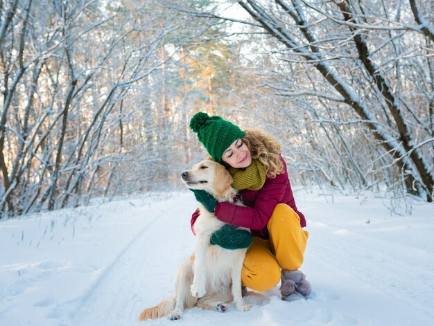 Retrato de mujer joven abrazando perro golden retriever blanco en invierno