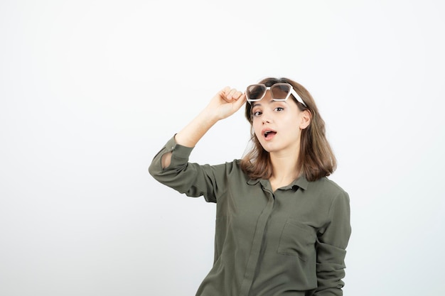 Retrato de mujer joven adorable en anteojos de pie sobre blanco. foto de alta calidad