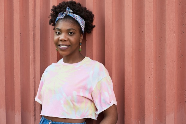 Retrato de mujer joven africana en ropa casual sonriendo a la cámara mientras está de pie al aire libre