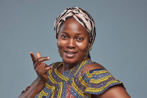 Retrato de mujer joven africana con velo y traje nacional mirando a la cámara contra el bac azul