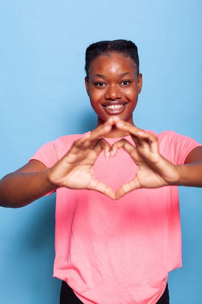 Retrato de mujer joven afroamericana cariñosa haciendo símbolo del amor