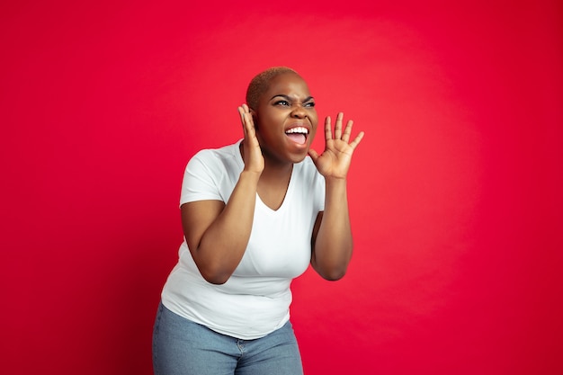 Retrato de mujer joven afroamericana sobre fondo rojo.