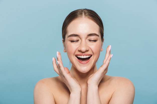 Retrato de una mujer joven alegre bastante feliz posando aislada sobre la pared azul.