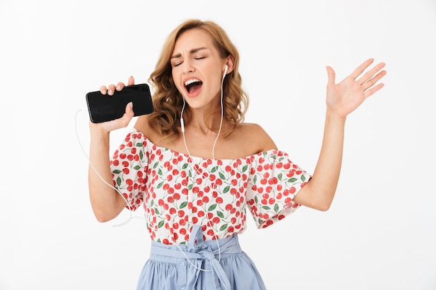 Retrato de mujer joven alegre cantando mientras escucha música con auriculares y smartphone aislado