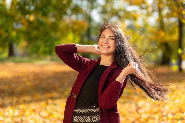 Retrato de una mujer joven alegre disfrutando en el parque de otoño.