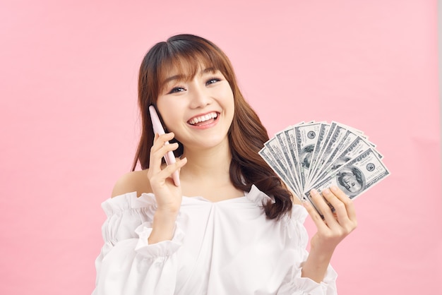 Retrato de una mujer joven alegre sosteniendo billetes de dinero y celebrando