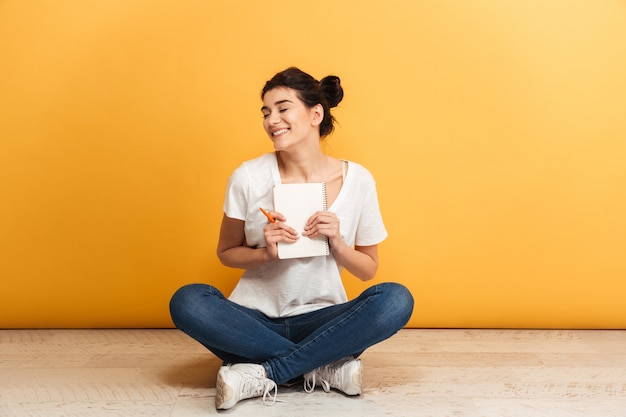 Retrato de una mujer joven alegre sosteniendo un cuaderno