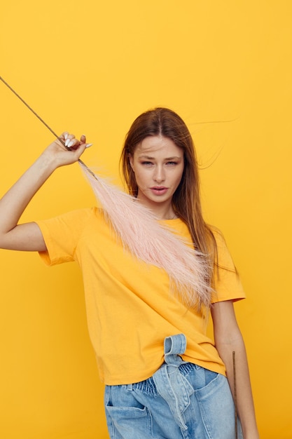 retrato, de, un, mujer joven, en, amarillo, tshirts, rosa, plumas, aislado, plano de fondo