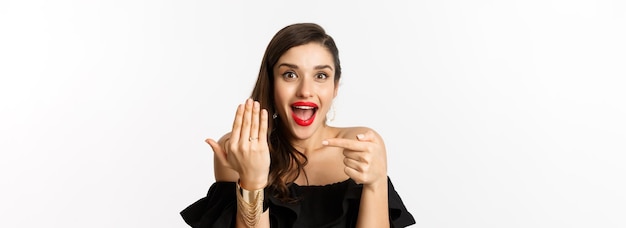 Retrato de una mujer joven aplicando maquillaje contra un fondo blanco