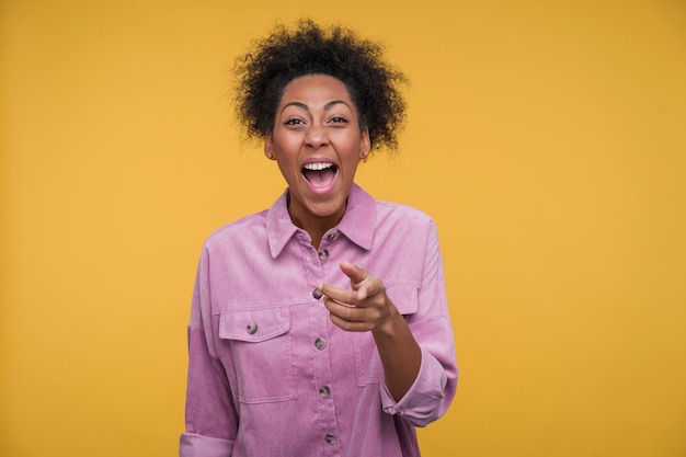 Foto retrato de una mujer joven apuntando a algo y riendo