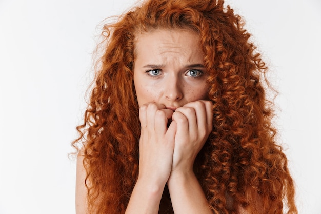 Retrato de una mujer joven asustada atractiva con el pelo rojo largo y rizado que se encuentran aisladas