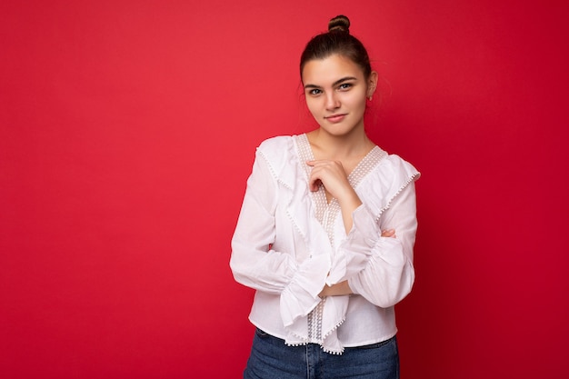 Retrato de mujer joven atractiva hipster caucásica en ropa casual de moda. Persona de sexo femenino despreocupado sexy posando aislada junto a la pared roja en estudio. Modelo positivo con maquillaje natural. Espacio vacio.