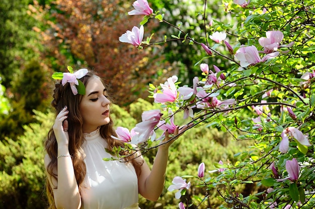 Retrato de mujer joven y atractiva en el jardín de primavera con magnolias en flor rosa. Fondo de primavera