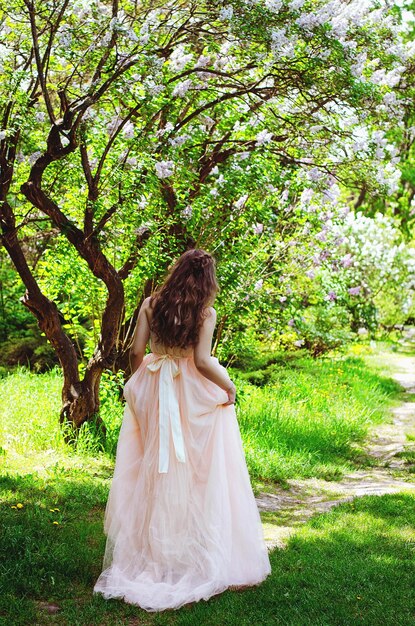 Retrato de mujer joven y atractiva en el jardín de primavera con un ramo de lilas. Fondo de primavera.