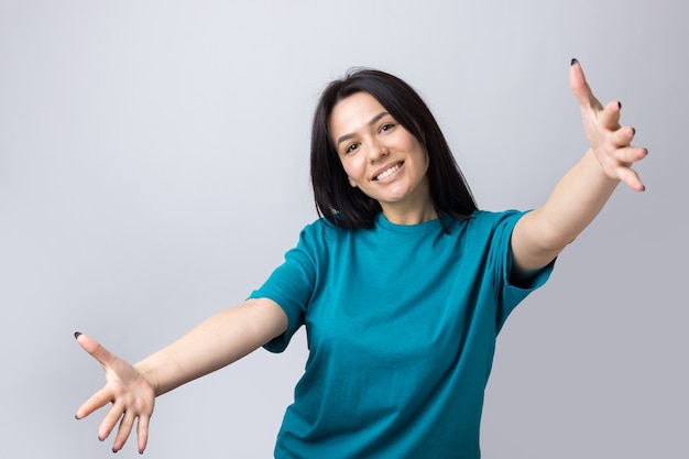 Retrato de mujer joven atractiva quiere abrazarte, aislado sobre fondo gris.