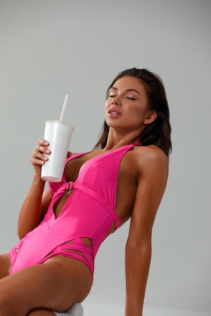 Foto retrato de una mujer joven bebiendo agua contra un fondo blanco