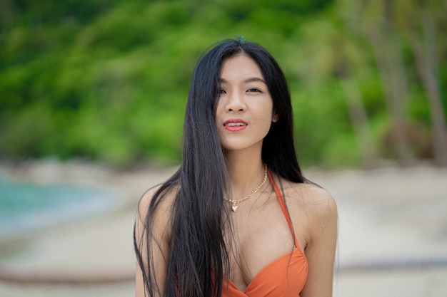 Retrato de mujer joven en bikini naranja en playa tropical