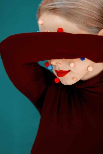 Retrato de mujer joven con bolas de colores en la cara