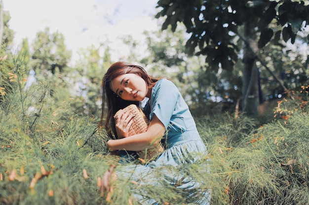 Foto retrato de una mujer joven con un bolso sentada en el campo