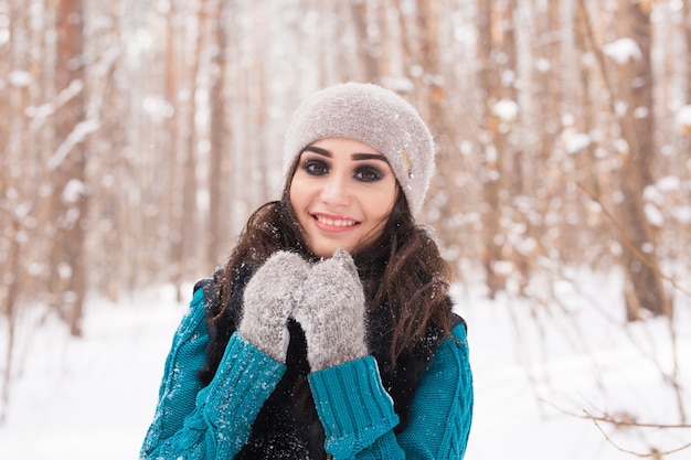 Retrato de mujer joven y bonita caminando en el parque cubierto de nieve de invierno en un día soleado
