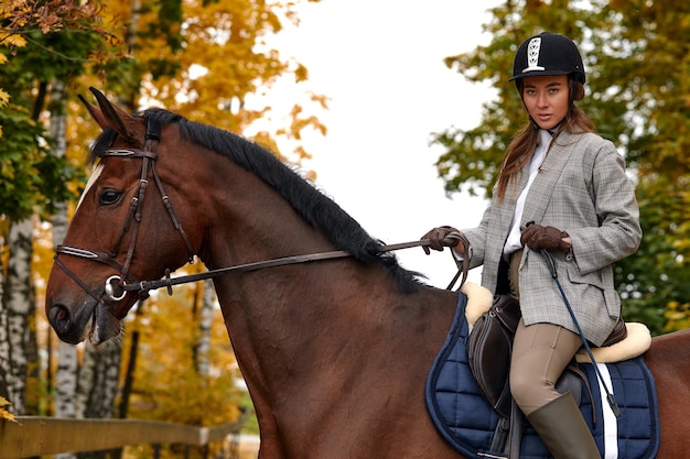 Retrato de una mujer joven y bonita con un día de otoño de equitación marrón