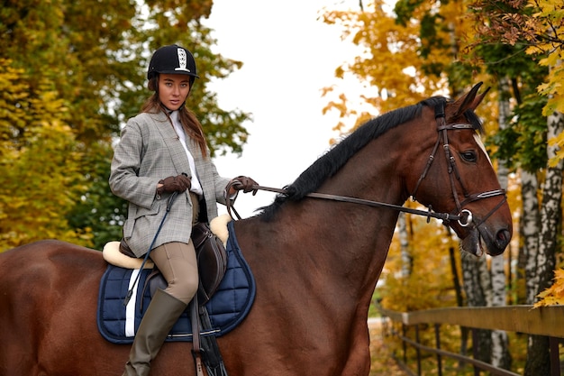 Retrato de una mujer joven y bonita con un día de otoño de equitación marrón